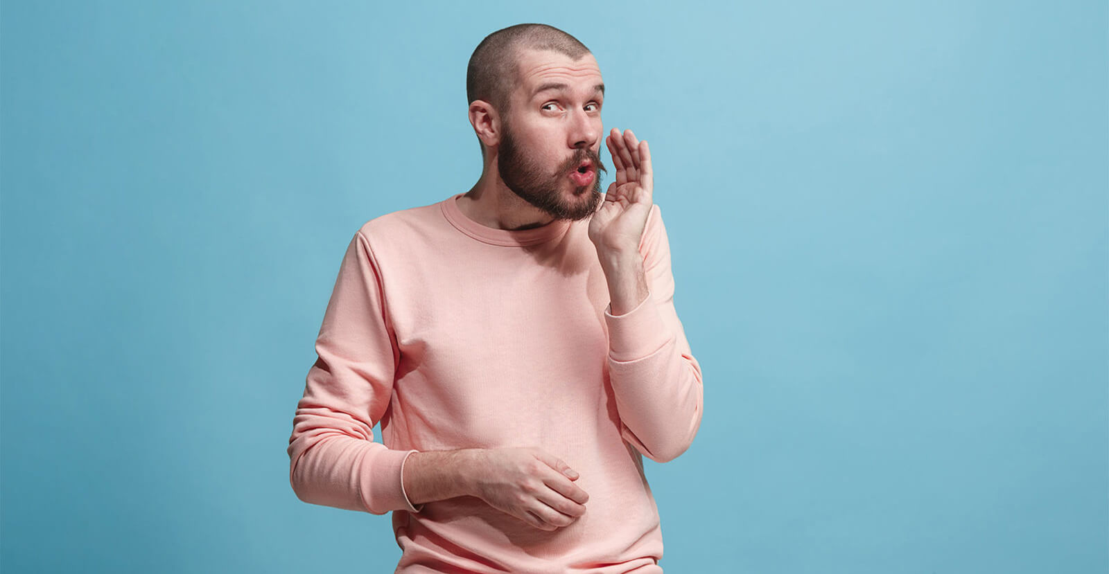 man whispering wearing pink shirt on blue background