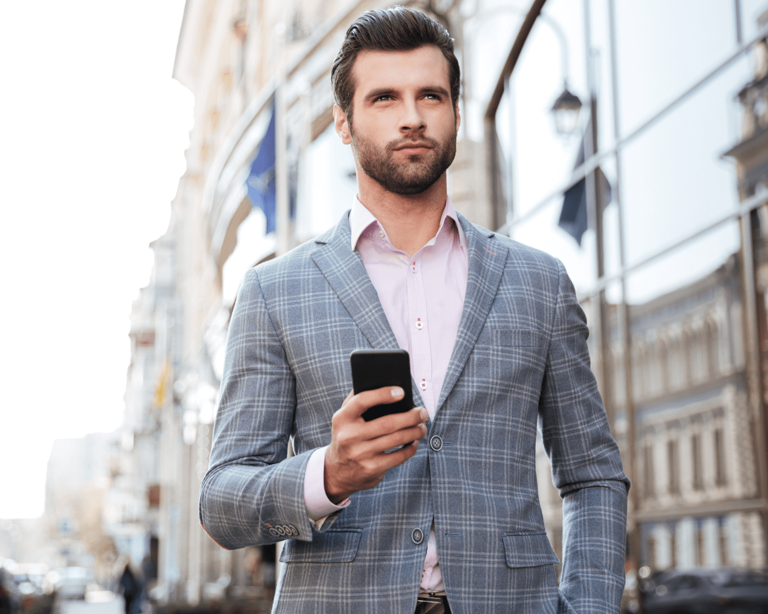 man walking along street with phone in hand wearing a suit