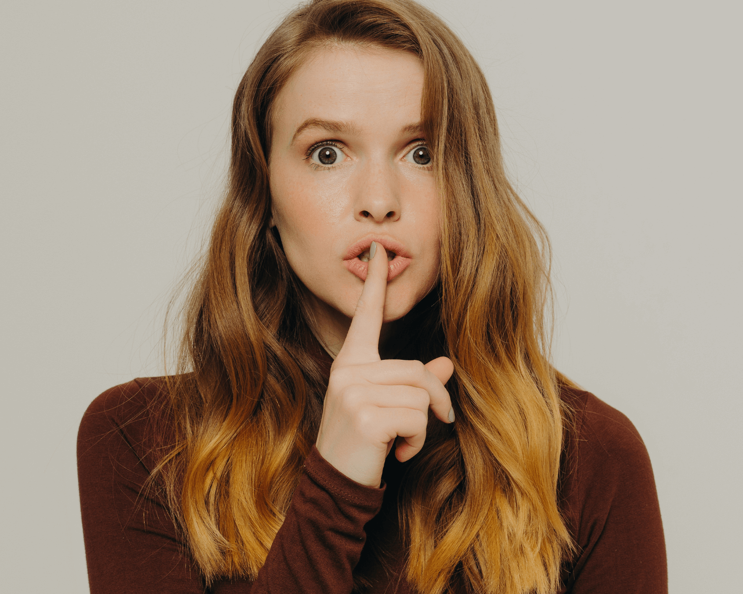 young woman with her fingers over her lips