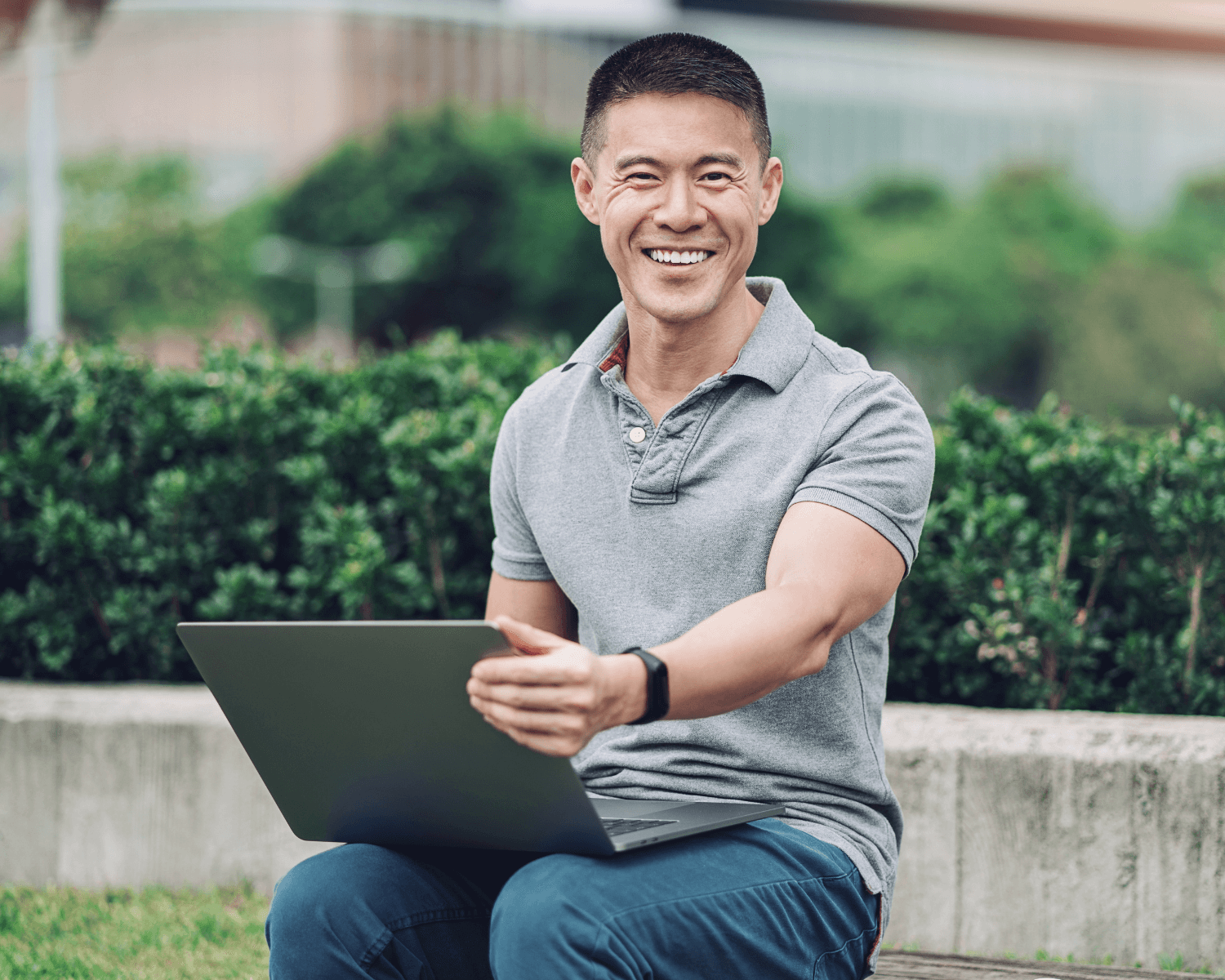 Man wearing grey shirt with laptop looking happy